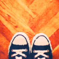 A picture of a pair of blue Converse high-top sneakers on a wooden parquet floor